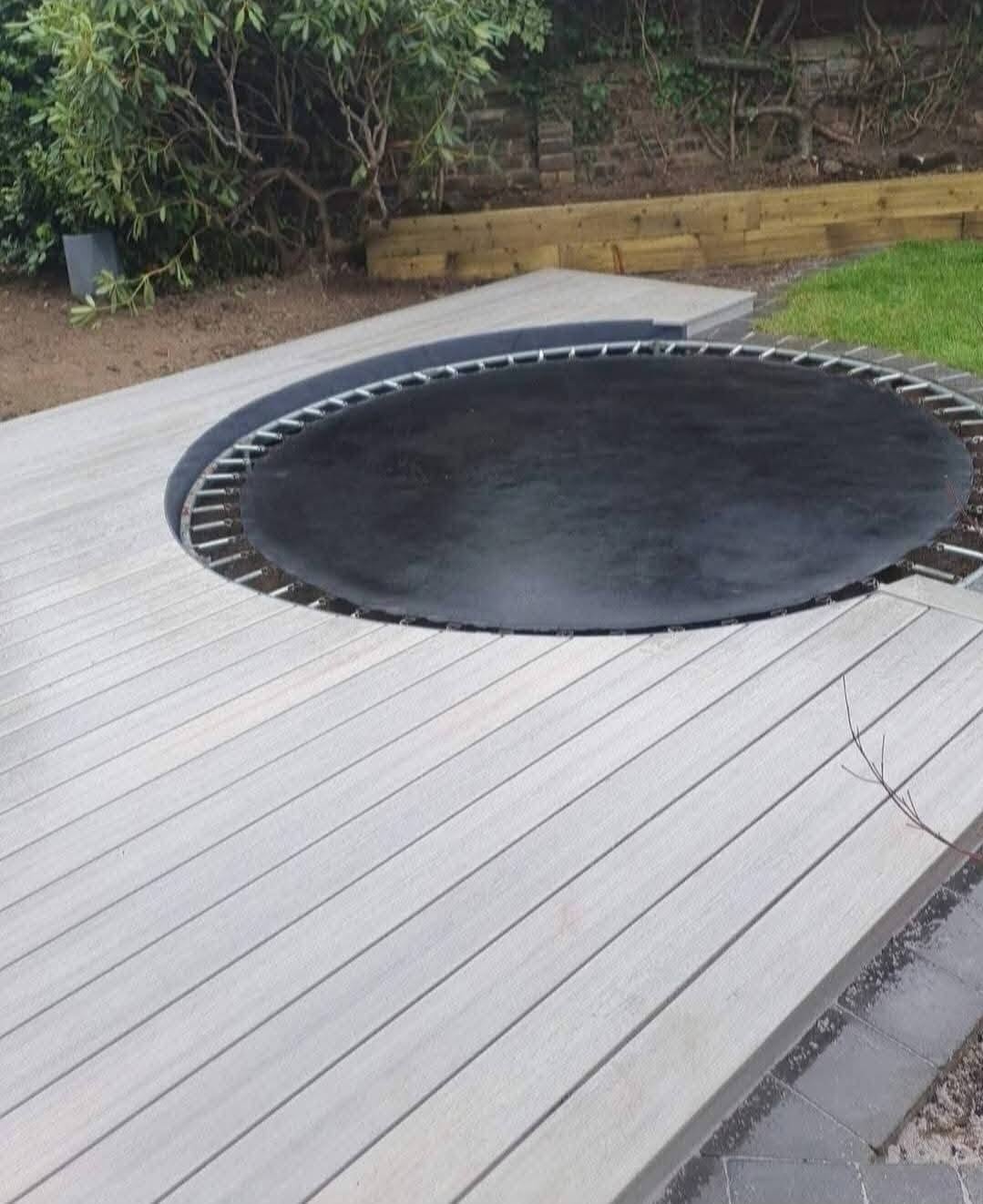 Grey decking with a recessed trampoline and lawn